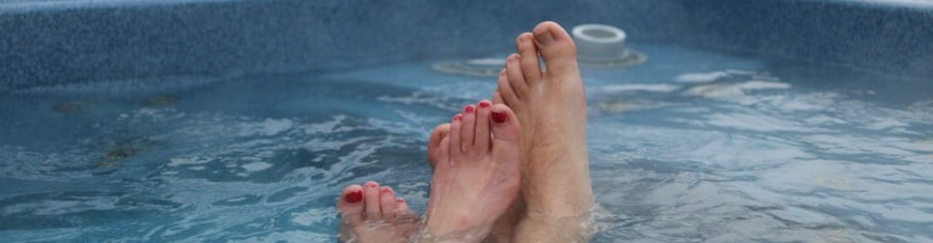 two pairs of feet soaking in a hot tub