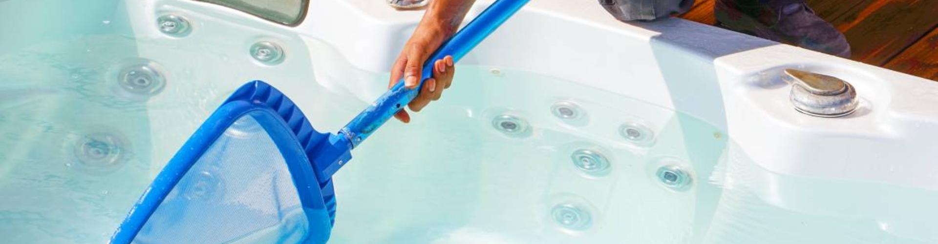 person holding a blue net to clean debris out if a tub