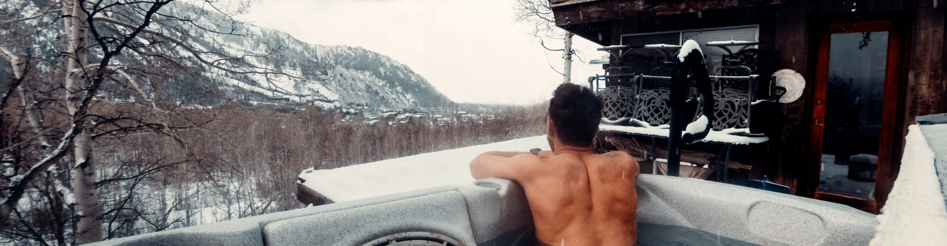 man sitting in an outdoor hot tub during the winter