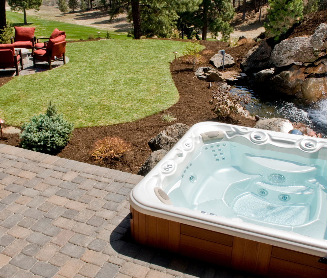 hot tub on pavers in a back yard overlooking a stream